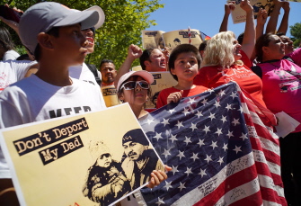 Un niño enseña una pancarta y la bandera estadunidense durante la marcha en defensa de los derechos de los inmigrantes ante la Casa Blanca