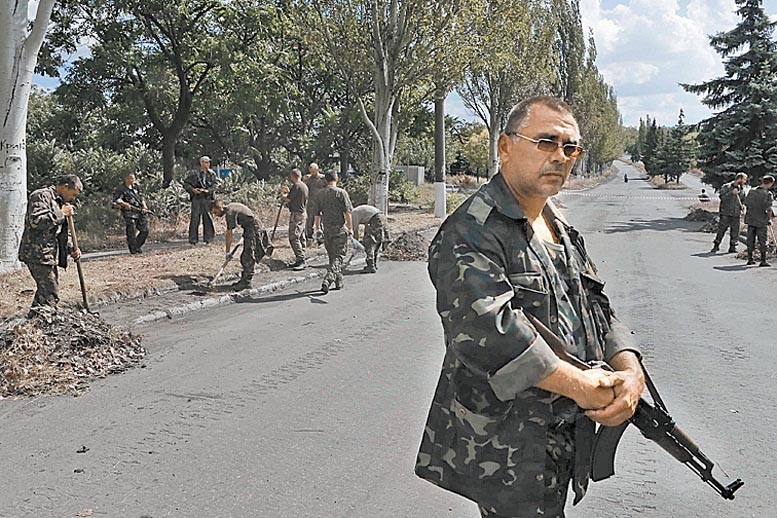 Rebeldes vigilan a soldados capturados que limpian una calle en Snizhne.