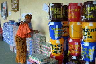 Una mujer prepara donaciones como parte de la lucha contra el virus, junto a unos recipientes especiales para lavarse las manos en Monrovia