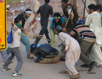 Seguidores del opositor Khan apalean a un policía antidisturbios en una manifestación en Islamabad