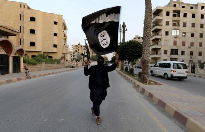 Un miliciano del Estado Islámico en Siria, con una bandera de los yihadistas