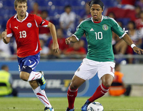 Giovani dos Santos se enfrenta ante un jugador de Chile 