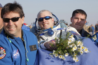 Especialistas rusos y de la NASA llevan a Steven Swanson (c) después del aterrizaje de la nave cerca de Zhezkazgan, en Kazajstán