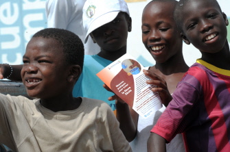 Varios niños senegaleses sonríen mientras uno lee un panfleto de información sobre la prevención del ébola en un suburbio de Dakar