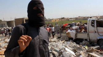 Un miembro del Estado Islámico, entre los escombros de una casa tras ser derribado un avión militar sirio en Raqa por los yihadistas