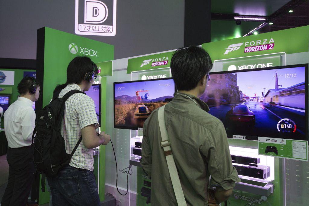 Visitantes jugando un videojuego de carreras de coche en consolas Xbox One.