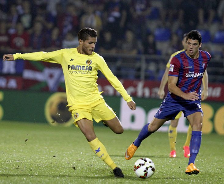 El centrocampista mexicano del Villarreal Jonathan Dos Santos (i) dispara ante el centrocampista del Eibar, Ander Capa (d)