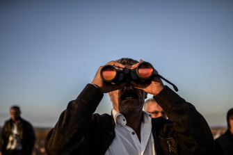 Un hombre observa con binoculares desde una colina turca las luchas entre yihadistas del EI y milicianos kurdos en el otro lado de la frontera