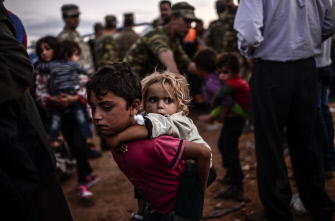 Un grupo de kurdos sirios llega a la frontera con Turquía después de que varios morteros impactaron en Suruc, en la provincia de Sanliurfa