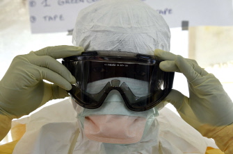Un trabajador sanitario en traje protector se pone las gafas en el centro de Médicos sin Fronteras (MSF) para tratamiento del ébola en Monrovia
