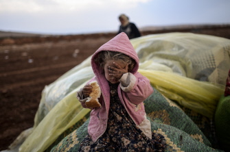 Una mujer kurda siria espera junto a su hija cerca de la frontera siria en la ciudad de Suruc en la provincia turca de Sanliurfa