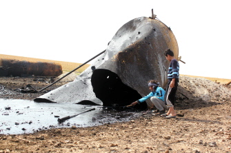 Niños juegan entre los restos de una refinería de petróleo del EI destruida por un ataque aéreo de la coalición internacional, en Tal Abyad, Siria