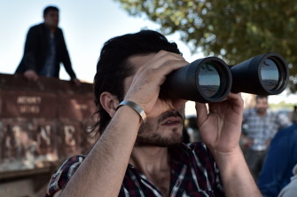 Un kurdo usa sus binoculares para observar los combates en la ciudad sirio kurda de Kobane, desde la villa turca de Mursitpinar