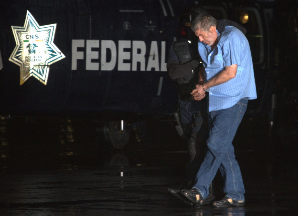 Vicente Carrillo Fuentes es trasladado por un policía federal a un helicóptero en el hangar de la PGR en el DF.