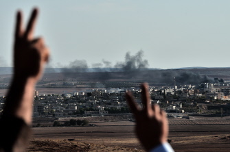 Kurdos hacen el signo de la victoria al observar desde la frontera sirio-turca el humo de los combates en Kobane