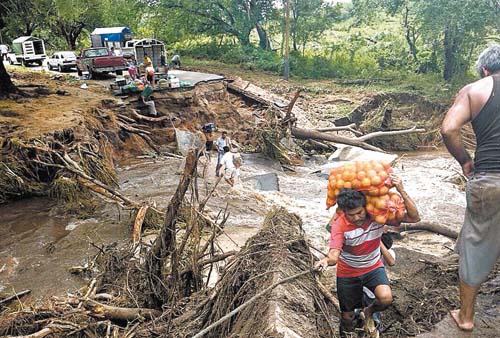 Ciudadanos cruzan un río con víveres para damnificados.