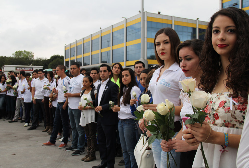 Alumnos de la UANL portan rosas blancas en la explanada de Rectoría.