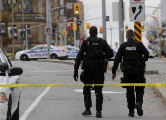 Oficiales de policía de Ottawa caminan en Wellington St., cerca del National War Memorial donde el soldado fue asesinado