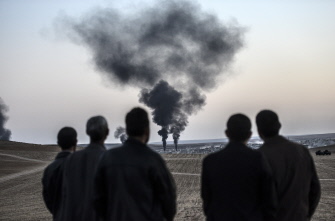 Varias personas miran como el humo de los combates asciende en la ciudad de Kobane, desde la ciudad turca de Mursitpinar