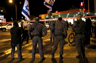 Fuerzas de seguridad israelíes protegen el lugar donde un derechista fue tiroteado por un palestino mientras otros ondean banderas israelíes