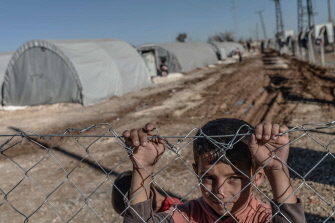 Un niño sirio kurdo mira a través de una valla de un campo de refugiados en la ciudad de Suruc, provincia de Sanliurfa, en Turquía 