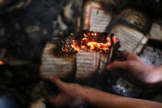 Un palestino enseña una copia del Corán ardiendo dentro de una mezquita incendiada por colonos israelies en Al Mughayir, cerca de Shilo