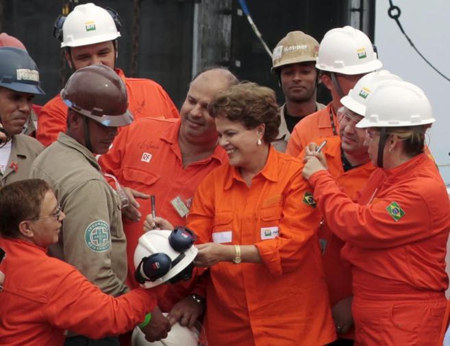 La presidenta brasileña, Dilma Rousseff, firma autógrafos a trabajadores en una planta de Petrobras durante la pasada campaña electoral
