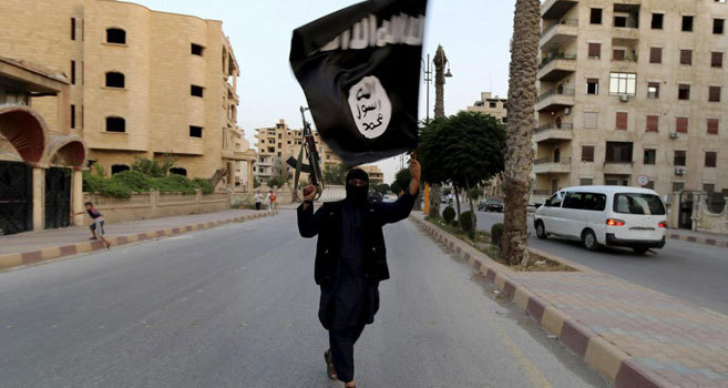 Un miliciano del Estado Islámico ondea una bandera del grupo yihadista en una calle de Raqa