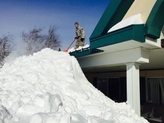 Un miembro de la New York Air National Guard asiste en las tareas de eliminación de nieve en el techo de un edificio en West Seneca, Nueva York