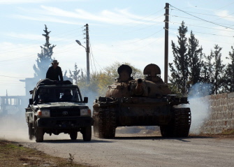 Rebeldes conducen un tanque y un auto armado en una carretera entre Zahraa y Nubol en la provincia de Alepo, en el norte de Siria