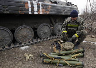 Un soldado ucraniano recarga su arma frente a un vehículo de transporte militar en la región de Donetsk