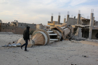 Un hombre camina junto a un minarete destruido tras un bombardeo de la aviación siria en Raqa, ciudad siria controlada por el Estado Islámico