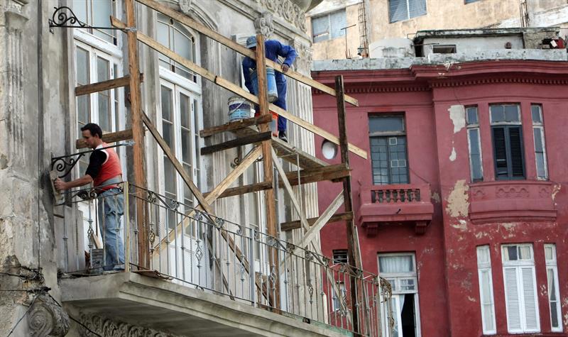 Dos hombres reparan el exterior de una vivienda hoy en La Habana 