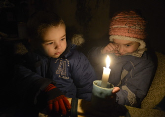 Dos niños sostienen una vela en un refugio en Donetsk, donde tres familias se han trasladado a vivir al ser destruidas sus casas en los combates