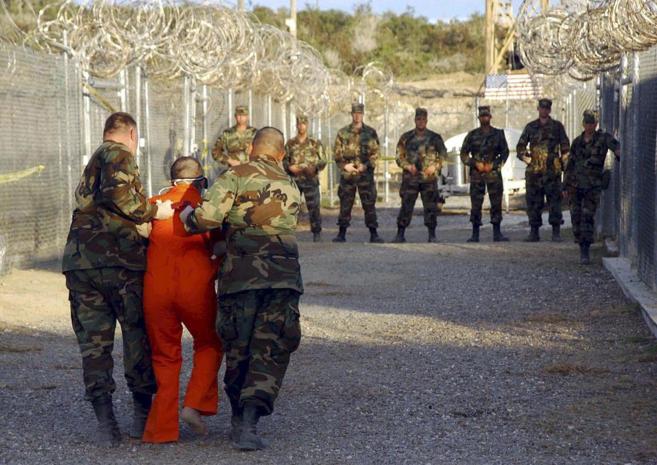 Dos soldados de EU trasladan a un preso de Guantánamo a su celda en 2002