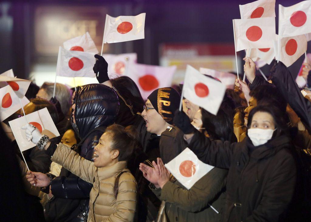 Los votantes que ondean banderas nacionales japoneses animan al primer ministro japonés, Shinzo Abe.