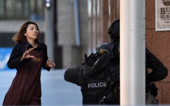Una joven, uno de los cinco rehenes que lograron escapar de la cafetería de Sidney, se dirige hacia un grupo de policías