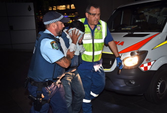 Un oficial de policía (i) y un paramédico (d) escoltan a un rehen que ha logrado salir de la cafetería en Sidney