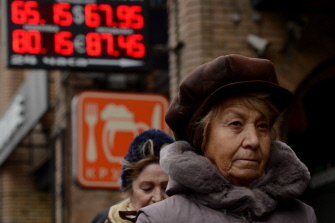 Una mujer rusa camina junto a una oficina de cambio de monedas de Moscú donde aparecen el valor de varias monedas respecto al rublo ruso