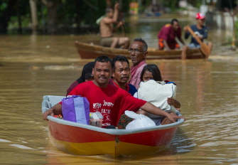 Una familia malasia intenta navegar en un bote en la villa inundada de Pengkalan Chepa, cerca de Kota Bharu