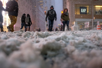 Varios peatones caminan por una calle cubierta de nieve en la céntrica Times Square, Nueva York, durante la tormenta de nieve 