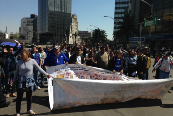 Los maestros llevan una manta en la que recuerdan a los 43 normalistas de Ayotzinapa desaparcidos.