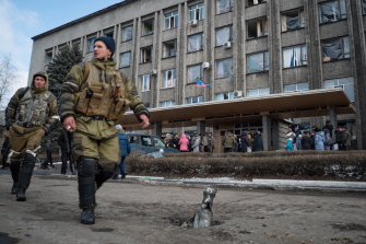 Dos soldados rebeldes pasean ante un edificio en el que se han reunido un grupo de ciudadanos en la ciudad de Debaltsevo