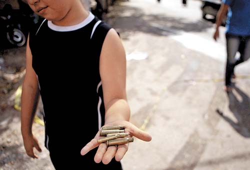 Un niño muestra cartuchos percutidos, tras el desalojo de la alcaldía de Apatzingán.