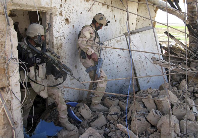 Dos soldados iraquíes investigan el escenario de un enfrentamiento entre las tropas del gobierno y milicianos del EI en Tikrit 