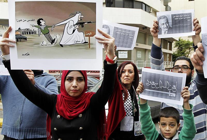 Varias personas muestran carteles que dicen "Dios maldice a Arabia Saudí" en una protesta ante la embajada saudí en Beirut, Líbano 