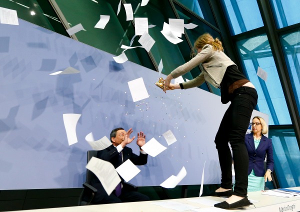 Una mujer que protestaba contra la política del Banco Central Europeo se subió sobre el escritorio del presidente de la entidad, Mario Draghi, mientra