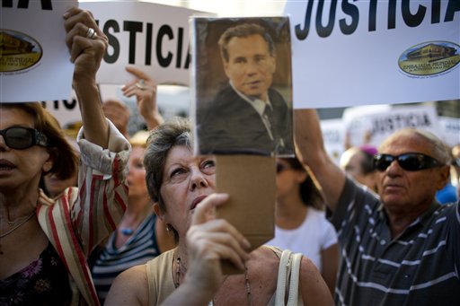 Una mujer canta el himno nacional argentino mostrando un retrato del fiscal Nisman en una manifestación ante la AMIA en Buenos Aires