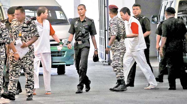 Dos de los sinaloenses, vestidos con el uniforme de los condenados a muerte, son escoltados por policías a la audiencia en el Palacio de Justicia.