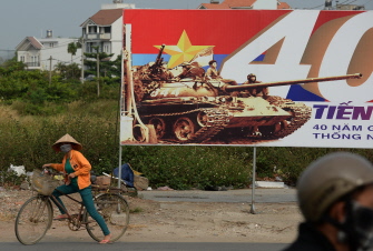 Un ciclista pasa junto a un cartel que recuerda el 40 aniversario de la tomaa de Saigon, hoy Ciudad Ho Chi Minh, por las tropas comunistas